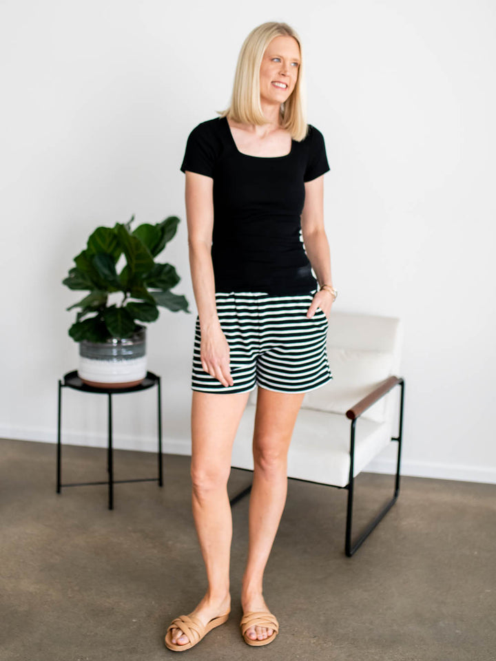 Tall model in black knit lounge shorts with white stripe and side pockets