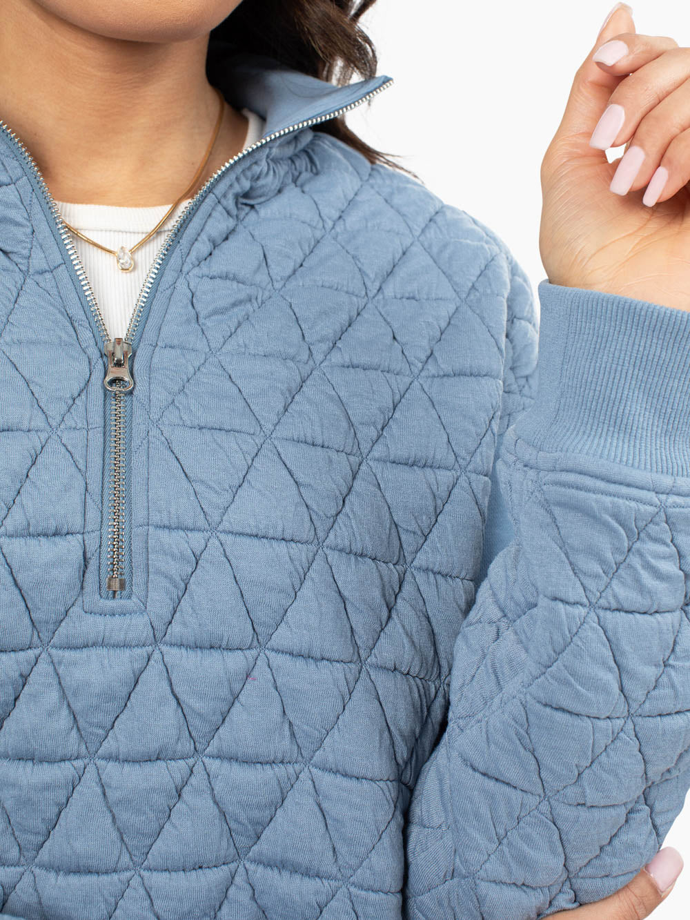 Close-up of quilted texture on blue half zip sweatshirt