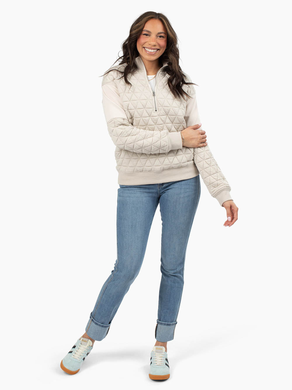 Tall woman wearing mushroom quilted half zip sweatshirt with jeans