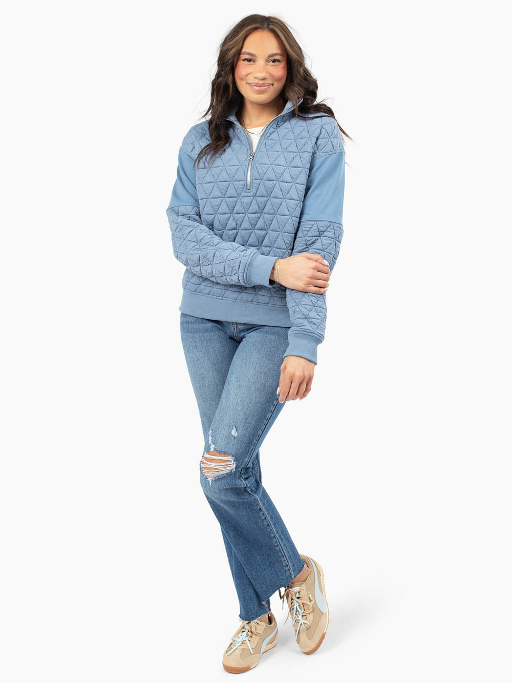 Tall woman wearing blue quilted half zip sweatshirt with jeans