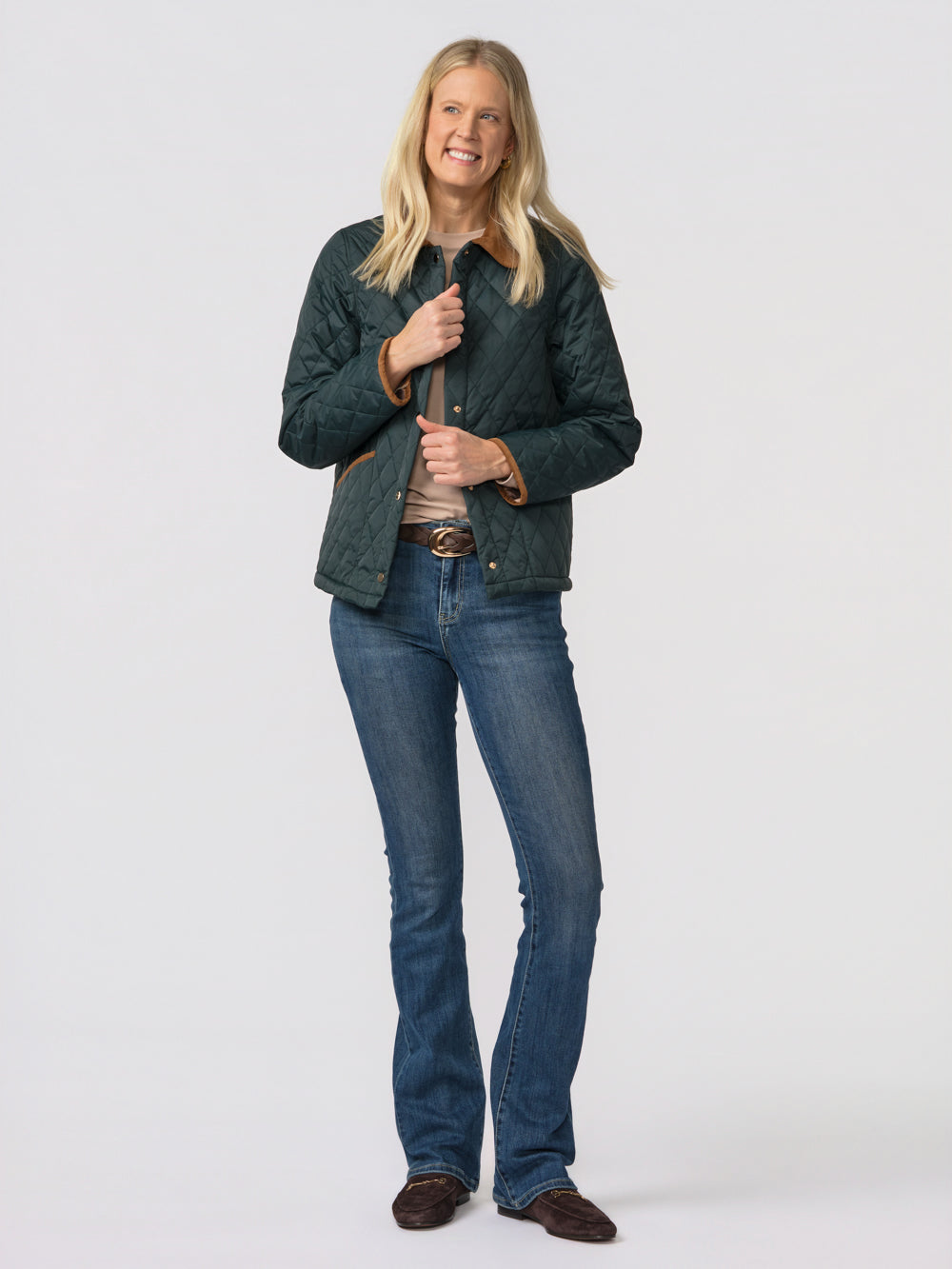 Tall woman in the green Langley quilted jacket styled with jeans and brown loafers