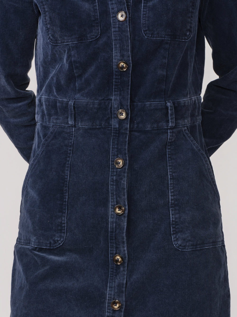 Close-up of the Odette cord dress's button front, defined waist and patch pockets
